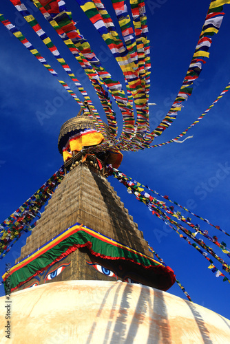 Boudhanath Stupa decorated with colorful Buddhist prayer flags against a deep blue sky in Kathmandu, Nepal