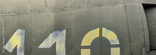 Texture of painted metal with rivets. Aluminum surface with scuffs, streaks. Green metal surface with rivets, secured panels in bright sunlight. The front of an old, abandoned military jet aircraft.