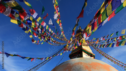 Boudhanath Stupa decorated with colorful Buddhist prayer flags against a deep blue sky in Kathmandu, Nepal
