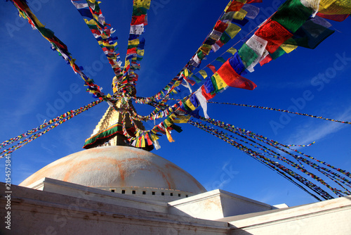 Boudhanath Stupa decorated with colorful Buddhist prayer flags against a deep blue sky in Kathmandu, Nepal
