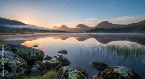 Calm lake reflection at sunrise with mountain range.