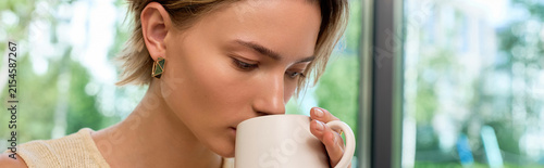 Cuadro en lienzo Stylish blonde woman enjoys coffee in a modern cozy cafe setting