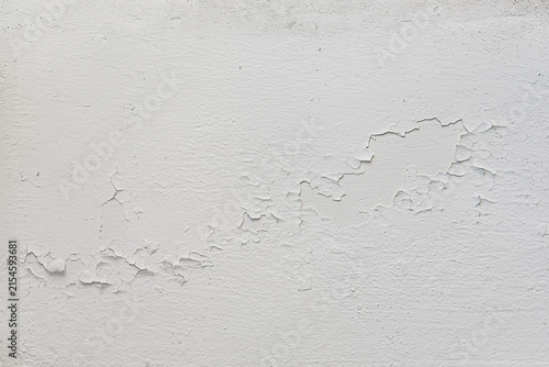 Close-up of an old white painted wall with cracked, flaking and peeling paint.