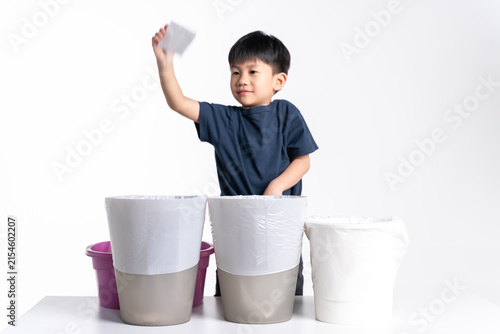A young boy disposes of a piece of paper into the correct trash bin, practicing proper waste sorting and recycling.