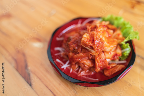 Foto A small dish of kimchi, a traditional Korean fermented cabbage, garnished with lettuce on a wooden table