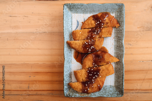 Fried fish or shrimp with sauce and sesame seeds on a rectangular plate.