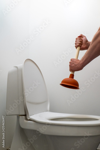 Vertical shot of a hand raising a plunger by a toilet