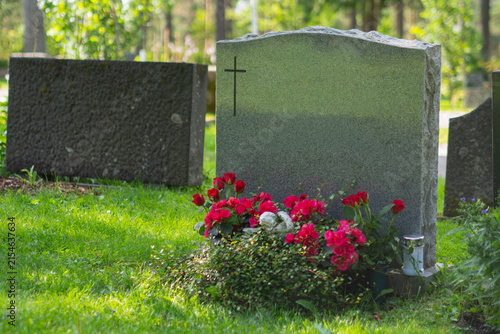 Engraved gravestone with cross and red roses