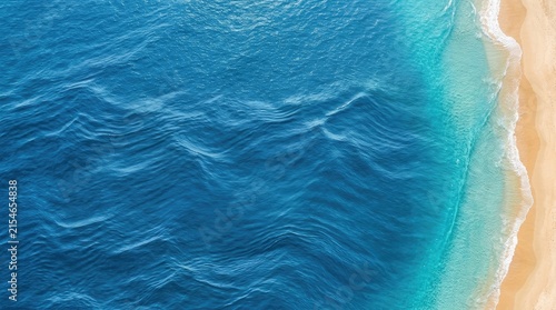 An aerial view captures the dynamic movement of turquoise ocean waves crashing onto a sandy beach.