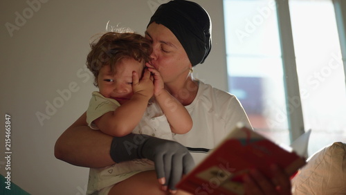 Obraz na płótnie Excited toddler reacts joyfully as his mother reads a picture book and kisses hi