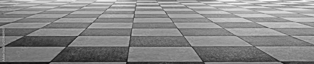 Fototapeta premium Black and white checkered floor tiles. Classic geometric pattern on polished stone. Clean lines define each square tile. Ideal for interior design projects. Subtle wear adds character to surface