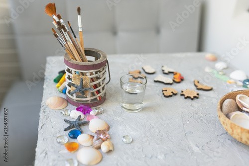 Kids creative art workspace with paintbrushes, seashells and wooden figures