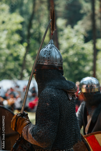 Fotografía Knights in chainmail and helmets stand in a forest, ready for battle while holdi