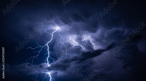 Bild auf Leinwand Powerful lightning bolt striking down through dark purple storm clouds with bril