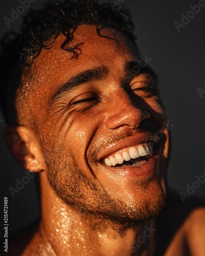 Joyful man laughing with wet teeth in natural light radiating happiness and glowing skin features
