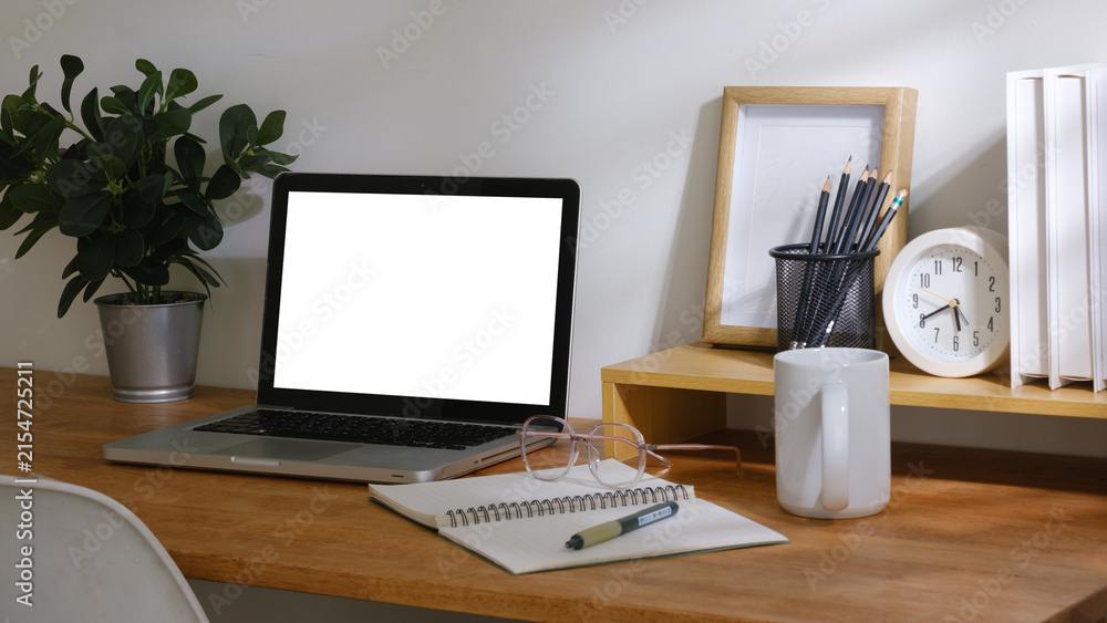 Fototapeta premium Minimal desk setup featuring laptop mockup, open notebook, books and office accessories, ideal for remote work, study and productivity concepts.