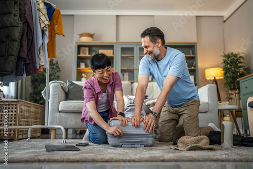 Happy couple packing suitcase for exciting vacation travel