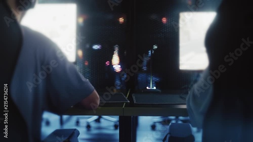 Two gamers playing a cooperative video game together in a modern computer club with purple lighting
