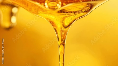 Close up of golden honey dripping with rich texture and natural sweetness on yellow background