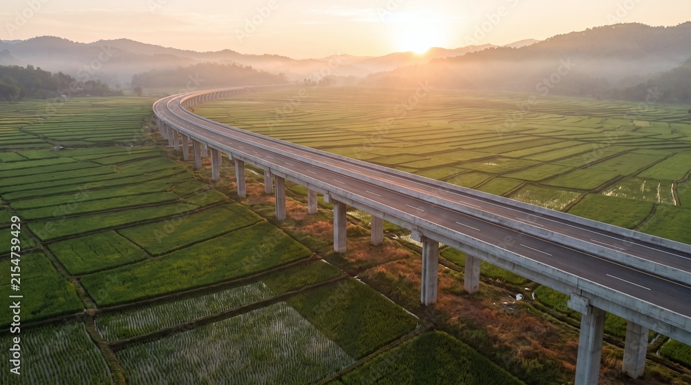 Fototapeta premium Aerial Scenic Highway Bridge Crossing Green Agricultural Fields at Golden Sunrise