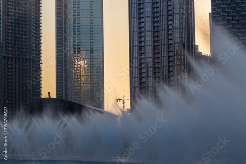 Sunset urban cityscape with water fountains and glass skyscrapers in Dubai, UAE