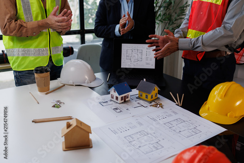 Фотография Construction professionals discussing architectural blueprints and residential m