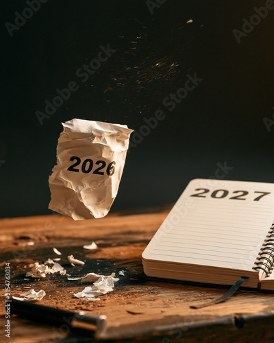 Zerknülltes Papier zeigt 2026 neben Notizbuch mit Aufschrift 2027