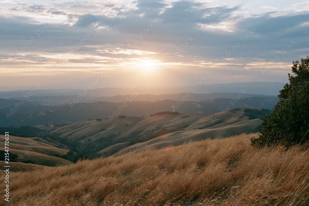 Obraz premium The Sunset Over Rolling Hills and Golden Grasslands at Distant Horizon