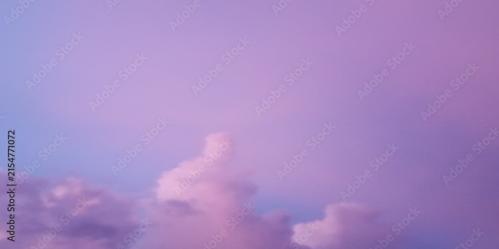 Fototapeta premium Dramatic purple sunset clouds over misty mountain landscape with soft light glow