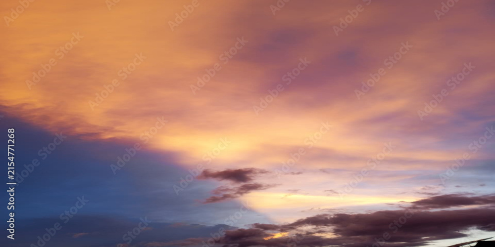 Fototapeta premium Dramatic sunset sky with vibrant orange and purple clouds over calm horizon