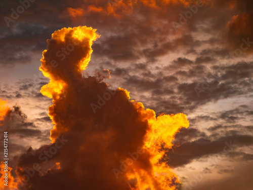 Quadro su tela Striking cloudscape at sunset in summer, with dark, anthropomorphic figure like a mythical giant on fire and in motion