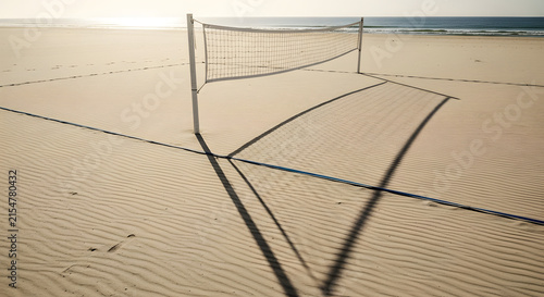 Beach volleyball net casting long shadows on sand.