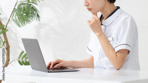 ノートパソコンの前で悩む女性