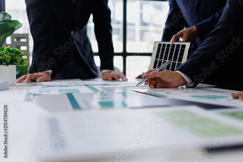 Business professionals discussing renewable energy strategy, analyzing solar power project data and sustainability reports