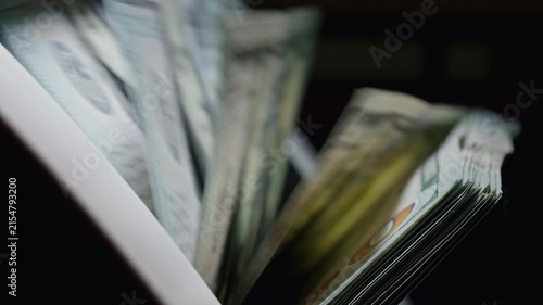 Close-up of US dollar banknotes counted by a cash counting machine. Perfect for currency exchange, international finance, banking and money transfer themes.