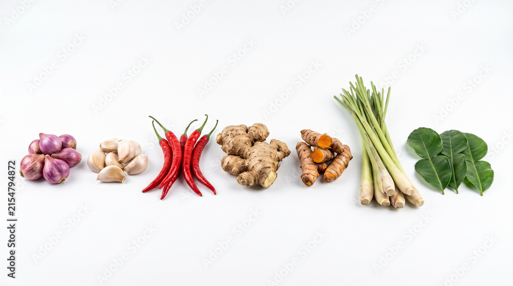 Fototapeta premium Spices and fresh herbs including ginger turmeric chili garlic lemongrass and lime leaves arranged in a neat row isolated white