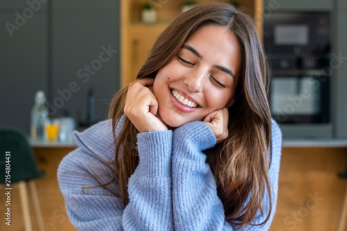 Quadro su tela Young woman in blue sweater smiling with eyes closed at home, relaxed and joyful