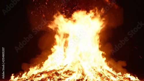 Powerful large bonfire flames burning with sparks against a dark background at night