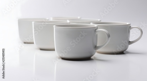 Group of white ceramic mugs arranged in a row on a white surface.