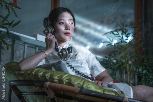 Принти на полотні Pretty young Chinese woman wearing white silk qipao and classic necklace talking