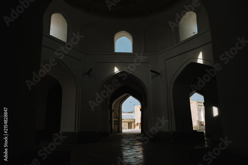 Dark interior of a historic building with arched doorways in Bukhara