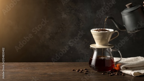Pouring hot water over coffee grounds in a pour over coffee maker with steam rising
