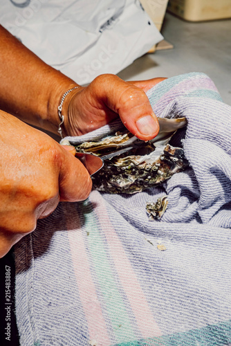 Close up of chef hands shucking a fresh raw oyster