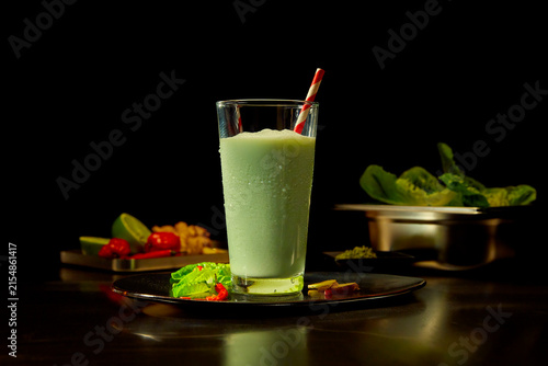 Smoothie im Glas mit Strohalm auf einem dunklen Teller