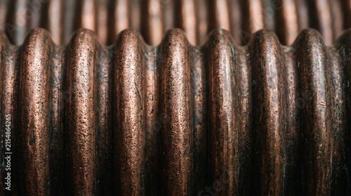 Corrugated copper metal texture with vertical lines. Industrial brown metallic background with rhythmic ridges and shadows. Abstract bronze ribbed surface for architectural design projects.