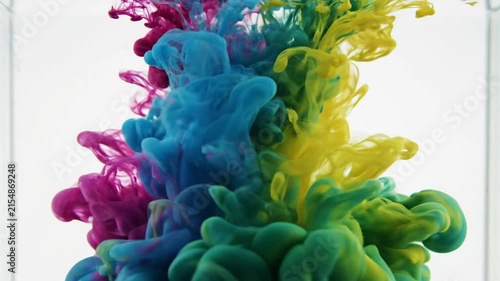 Colorful inks blending together in clear water creating vibrant, dynamic cloud-like forms for abstract art background