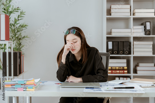 Konstfotografi Stressed Woman at Desk: A tired businesswoman rubs her eyes, overwhelmed by a messy desk piled high with paperwork