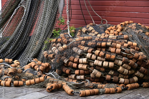 Close-up of traditional commercial fishing nets piled with weathered cork floats and marine gear, showing the textures and equipment used by the fishing industry.
