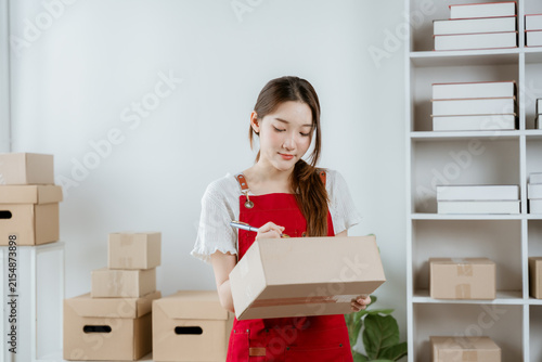 Foto Entrepreneurship in Action: A focused young woman, an aspiring entrepreneur, meticulously packages an order in her home office, surrounded by an organized shelving unit filled with inventory