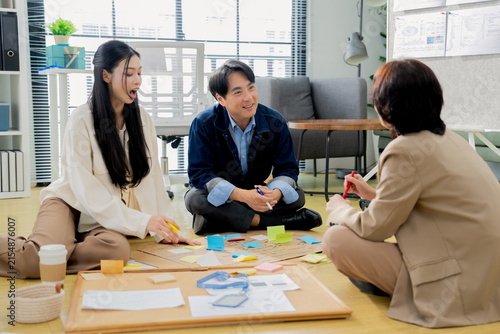 Business team brainstorming with sticky notes on floor, casual creative discussion during startup workshop, colleagues sharing ideas and collaborating on project board concept
